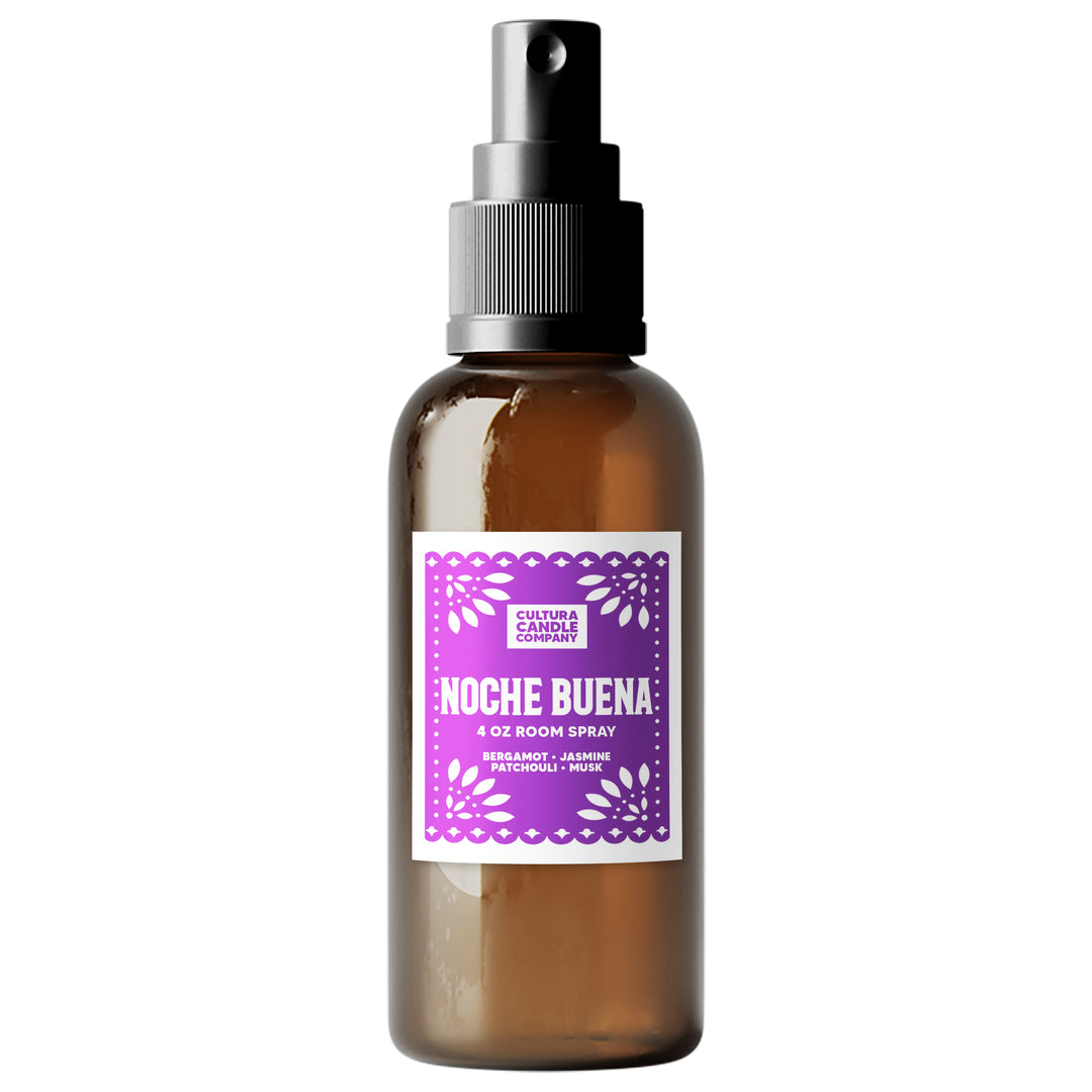 An amber glass room spray bottle with a black spray nozzle and a purple and white label reading 'Noche Buena' by Cultura Candle Company, shown on a plain white background.