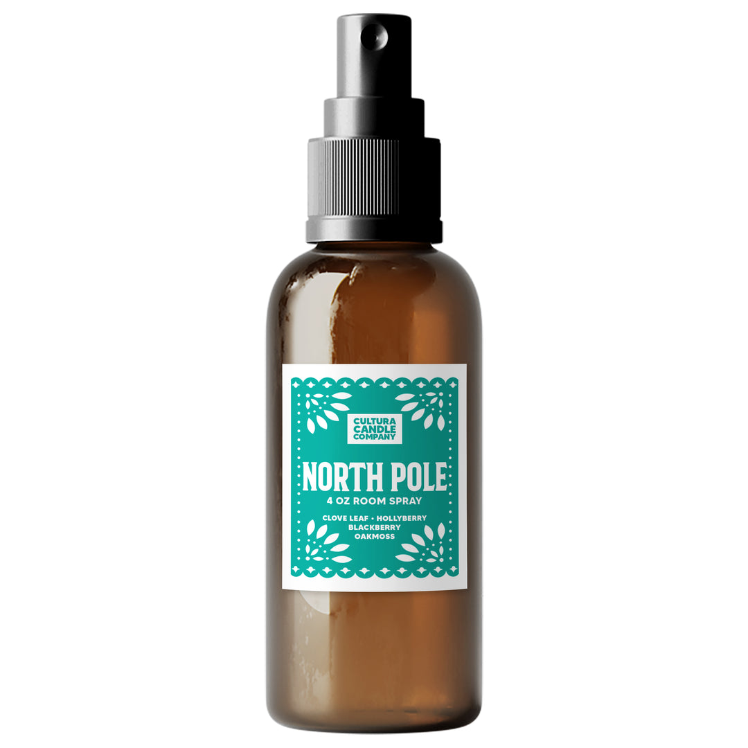 An amber glass room spray bottle with a black spray nozzle and a white label featuring a teal patterned border. The label reads 'NORTH POLE 4 OZ ROOM SPRAY' and 'CULTURA CANDLE COMPANY'.